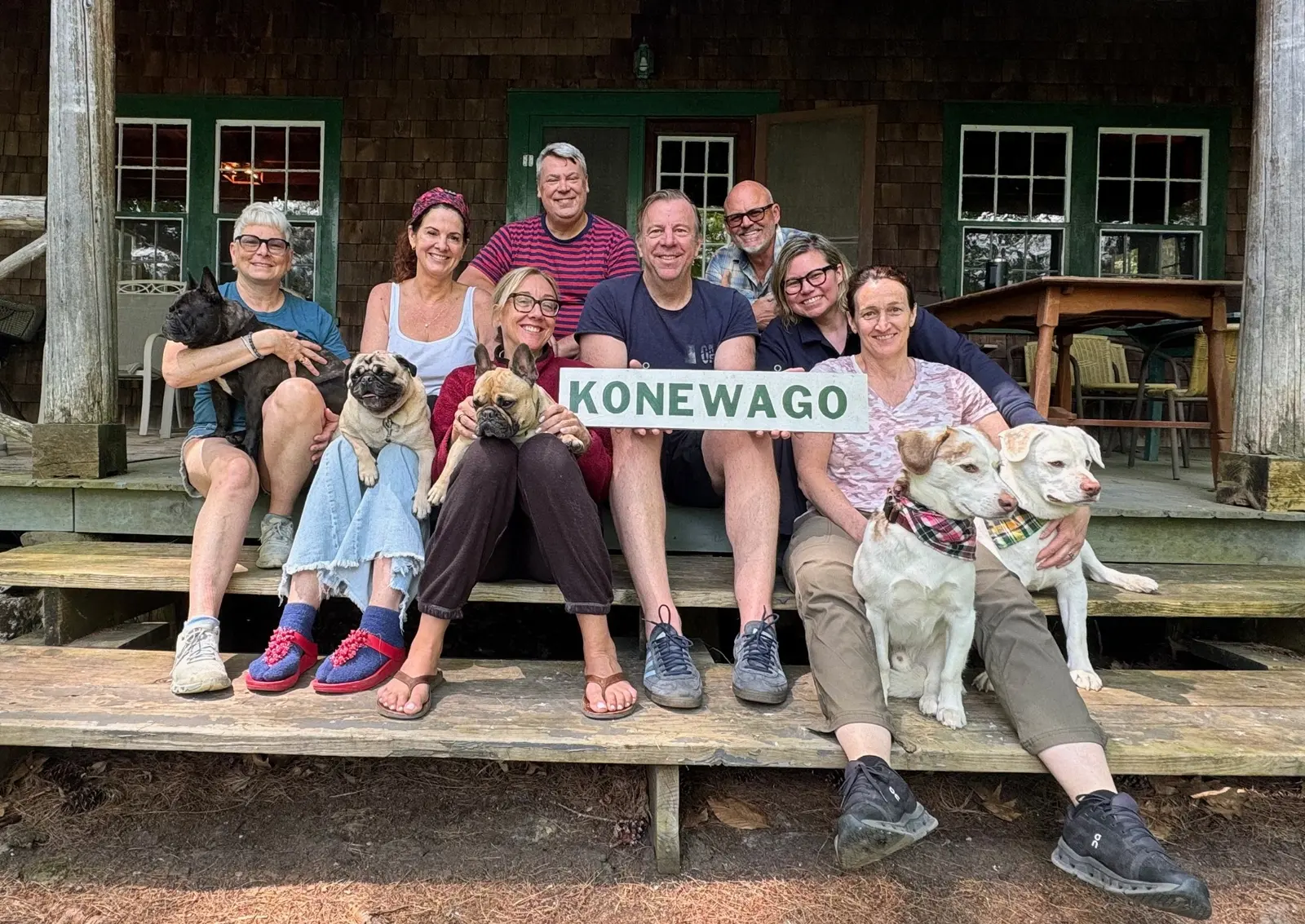 A group of friends and dogs gathered on the Camp Konewago porch
