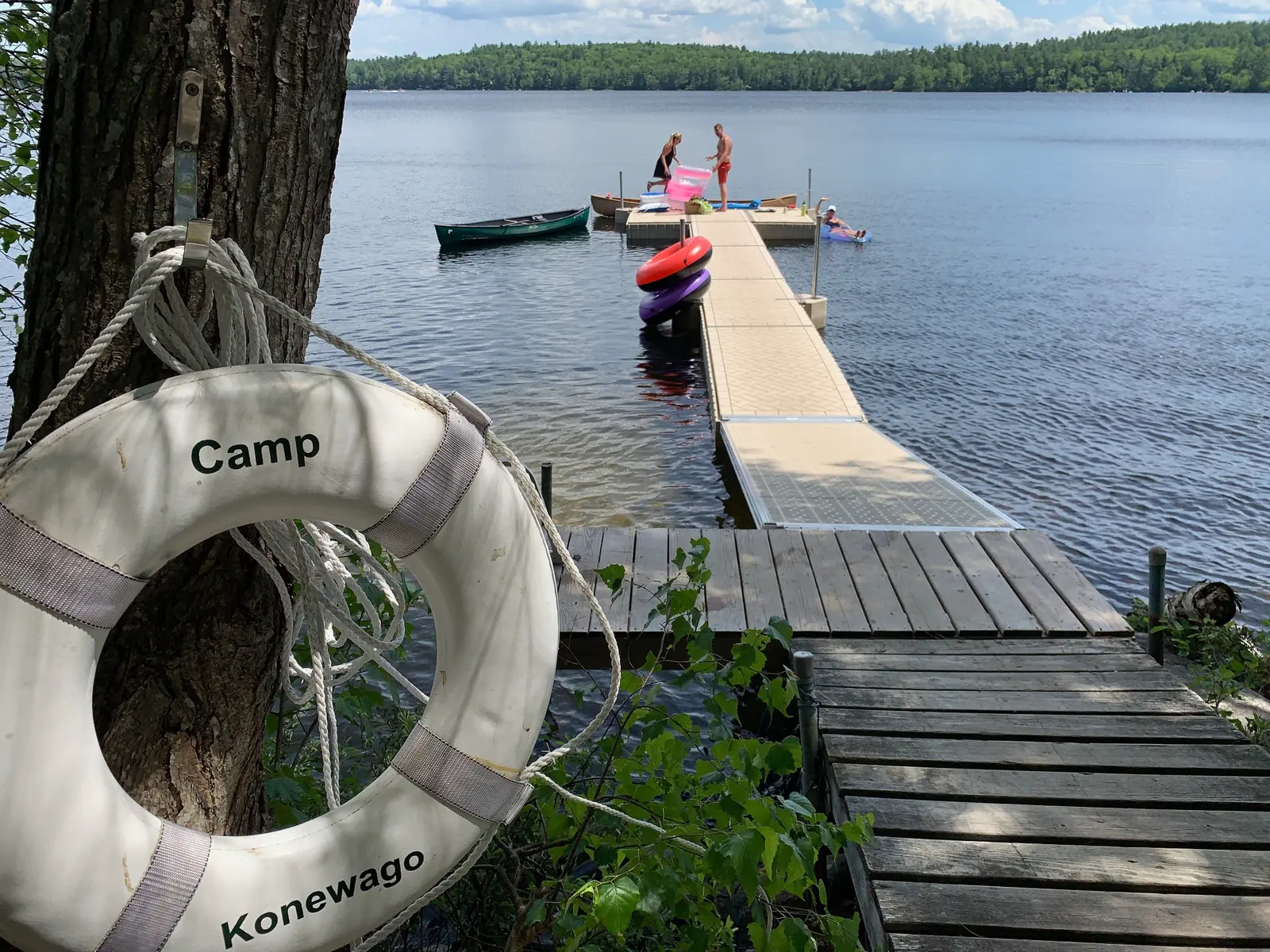 People enjoying the dock, canoes and lake on a summer day