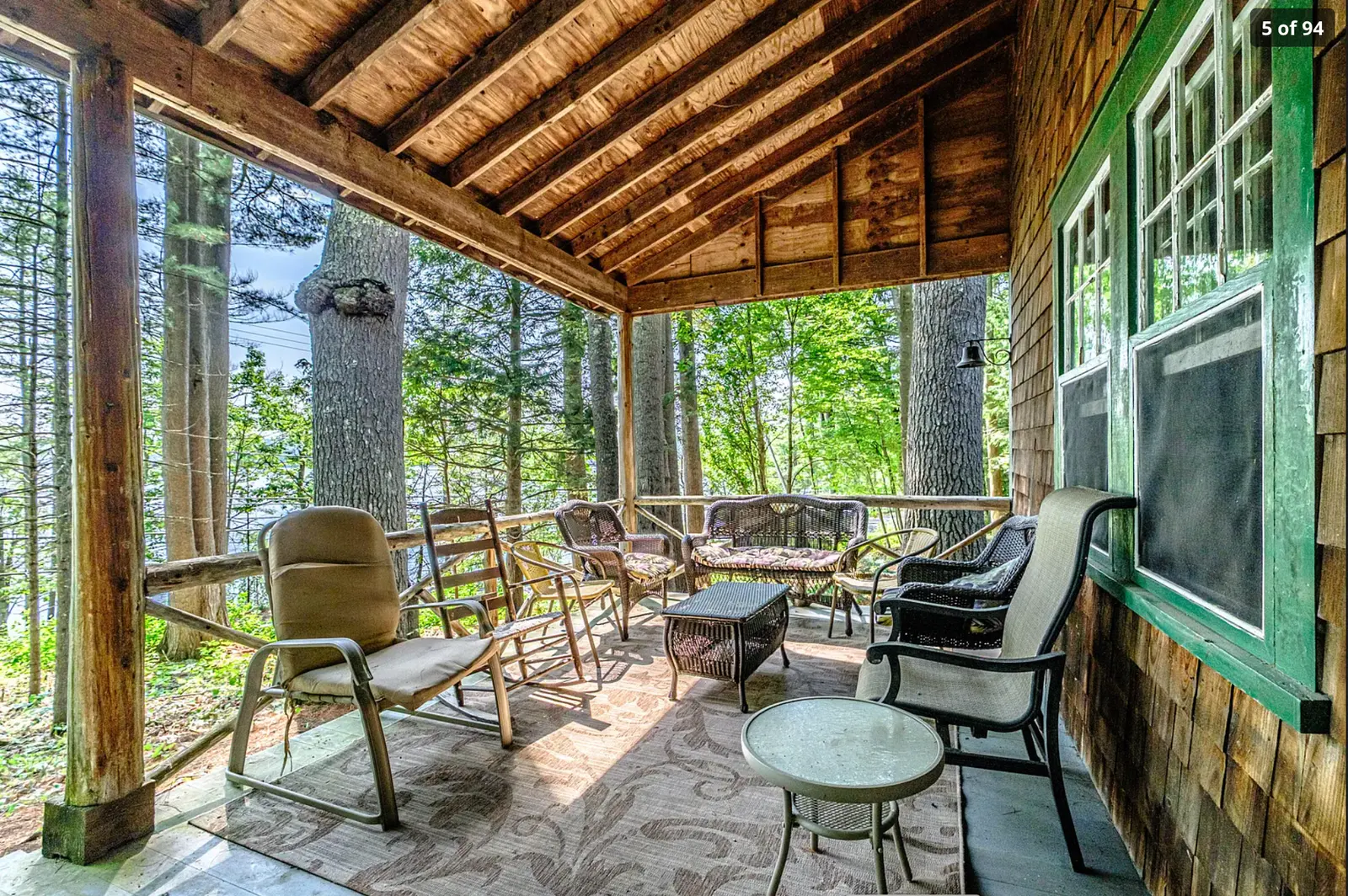 Long covered porch with chairs overlooking the woods