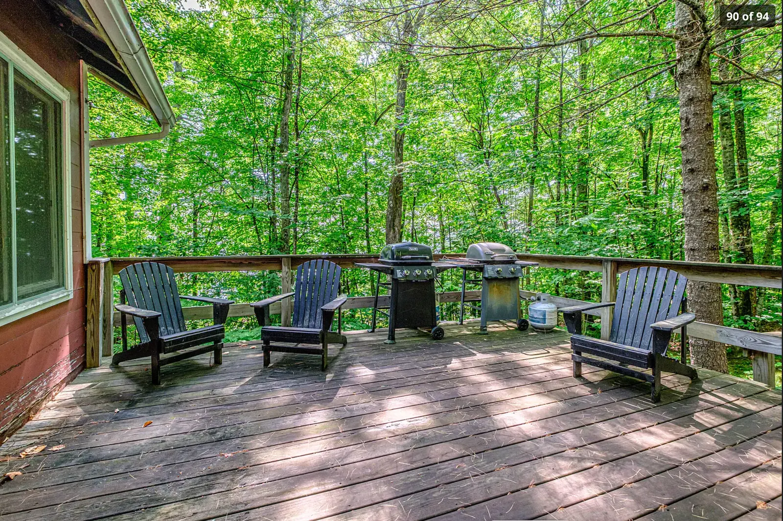 Large wooden deck with Adirondack chairs and grills